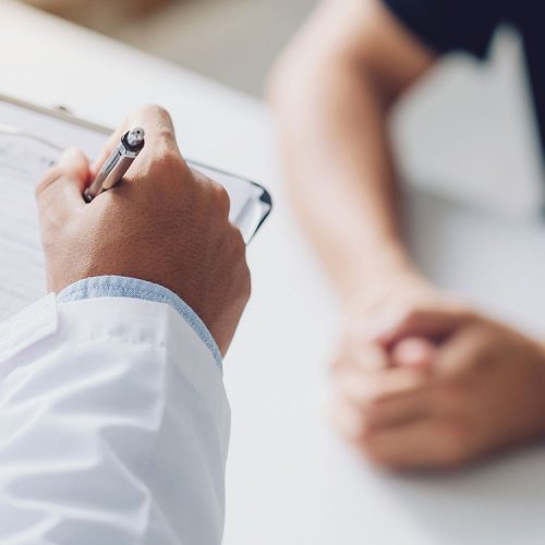 Arzt oder Gutachter füllt ein Formular während einer Untersuchung aus – Unfallgutachten