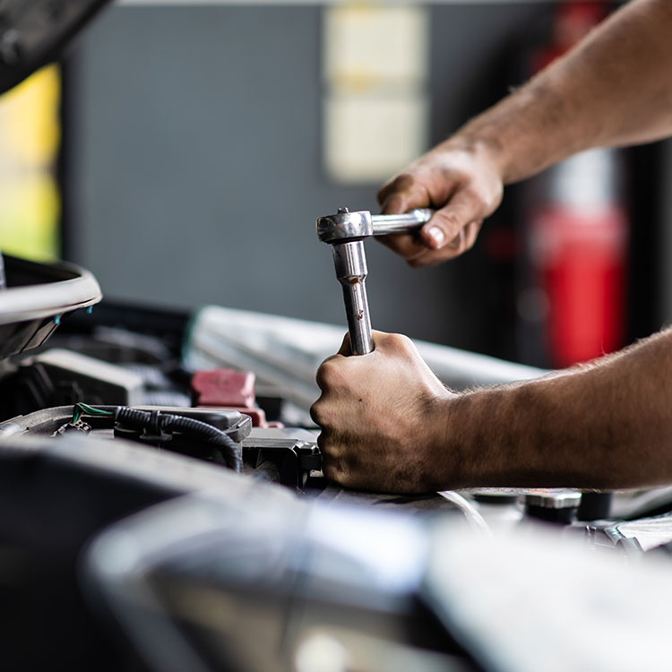 Mechaniker arbeitet mit einer Ratsche am Motor eines Fahrzeugs – Unfallgutachten